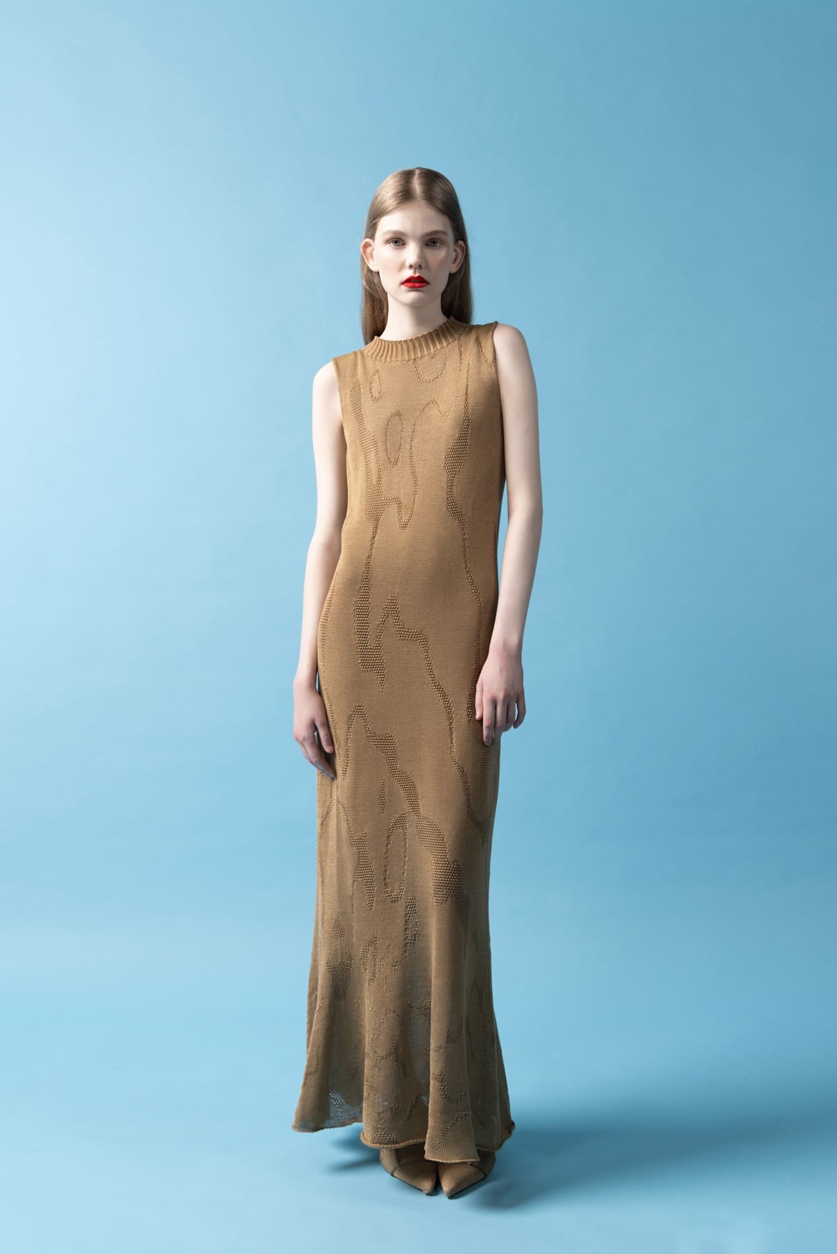 a model in a brown A-line dress against a blue background